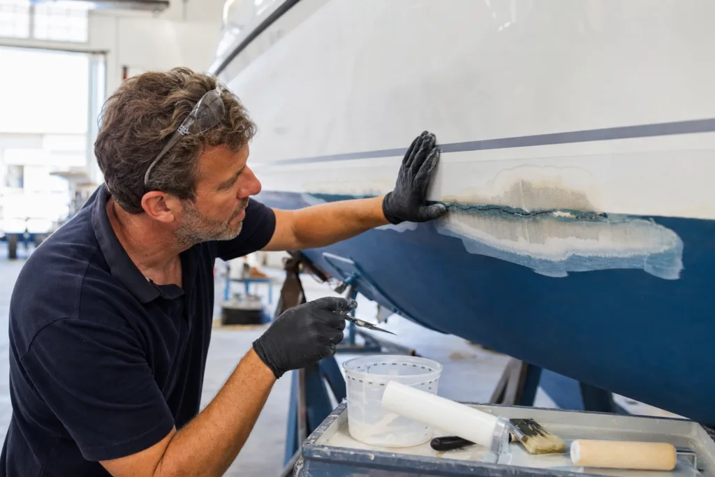 A boat hull repair scene showing inspection and preparation before choosing an epoxy resin system for structural fiberglass work.